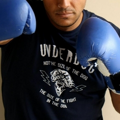 Homem em posição de boxe usando luvas azuis e a camiseta azul UNDERDOG da marca LK-LIKE com estampa de um cachorro bravo.