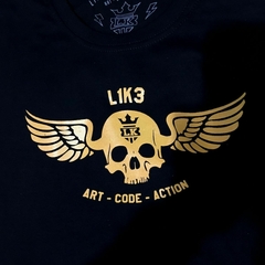 Camiseta preta da marca LK-LIKE com estampa de crânio dourado e asas, destacando as palavras "L1K3 ART - CODE - ACTION".