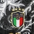 Emblema da seleção italiana de futebol em uma camisa preta com detalhes em branco e dourado.