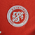 Emblema do Sport Club Internacional em uma camisa vermelha.