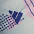 Detalhe do tecido da camisa do goleiro da Seleção da Espanha, com estampas em azul e rosa, destacando o logo da Adidas.