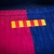 Detalhe da camisa Barcelona I 24/25, mostrando o emblema com as cores azul e vermelha.