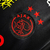 Logotipo do Ajax em uma camisa preta, com detalhes em vermelho e estrelas, representando a edição especial para torcedores.