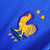 Emblema da Seleção Francesa com um galo amarelo e estrelas em um fundo azul.