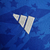 Logotipo da Adidas em uma camisa azul do Cruzeiro, destacando detalhes em branco e o padrão de estrelas ao fundo.