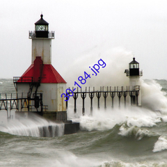 Imagen de un faro rojo y blanco en un día tormentoso con olas grandes rompiendo en el muelle.