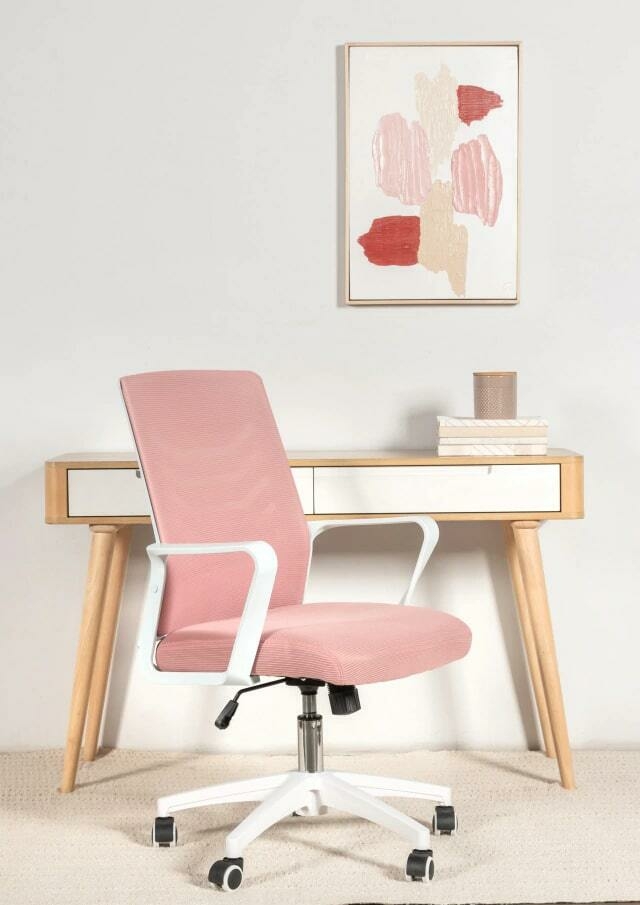 Una oficina rosa con un escritorio negro y una silla negra.