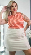 Modelo usando blusa regata feminina plus size listrada em tons de laranja e branco, combinada com saia clara.