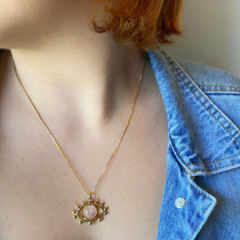 detalhe na modelo do colar semijoia em formato de olho grego com pedra quartzo rosa banhado a ouro 18k