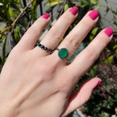 detalhe da combinação com o anel semijoia de pedra oval cristal esmeralda leitosa com aro torcido banhado a ródio negro
