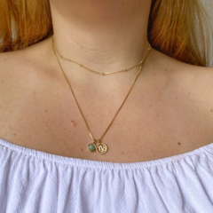 detalhe na modelo do colar semijoia do signo Capricórnio com pedra quartzo verde banhado a ouro 18k