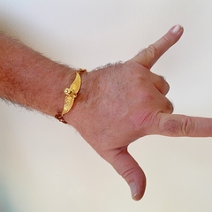 detalhe no pulso da pulseira semijoia handmade masculina de couro sintético marrom e pingente caveira com asa banhada a ouro 18k