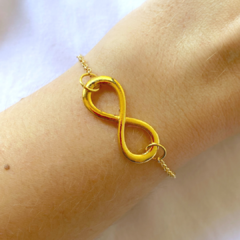 detalhe na modelo da pulseira semijoia feminina de corrente com pingente infinito banhado a ouro 18k