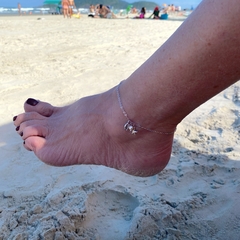 detalhe no tornozelo da tornozeleira semijoia corrente com pingentes estrela do mar, búzio e pérola banhado a ródio