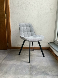 Silla Hamburgo tapizada en tela gris con base negra, diseño moderno y cómodo.