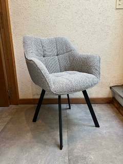 Sillón tapizado en tela gris con brazos y patas negras.