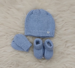 Conjunto de inverno azul composto por um gorro, luvas e sapatinhos de bebê.