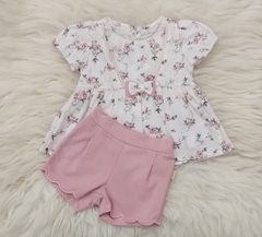 Conjunto de duas peças para crianças, com blusa floral branca e short rosa.