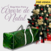 Bolsa organizadora verde para árvore de Natal, com alças brancas, em frente a uma árvore decorada.