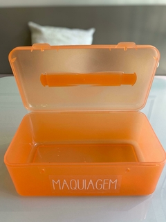 Necessaire Frasqueirinha Laranja com etiqueta de Maquiagem aberta em cima da mesa.