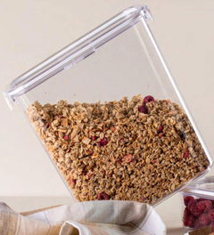 Pote slim multiuso transparente com granola e frutas vermelhas dentro, inclinado sobre uma superfície clara.