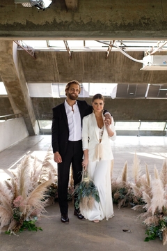 Casal de noiva e noivo abraçados vestindo conjunto de terno.