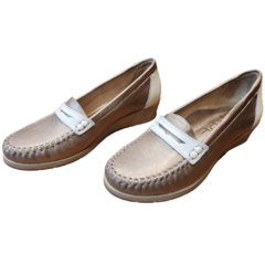 Mocasín Asis en tono dorado con detalles en blanco, ideal para un look casual y elegante.