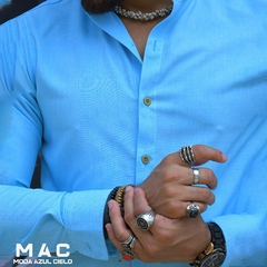 Camisa de Lino azul cielo Slim fit de manga larga con botones, mostrando manos con varios anillos y pulseras.