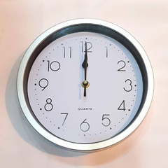 Reloj de pared plateado con fondo blanco