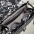 a imagem mostra o interior de uma bolsa baú com alça tiracolo e de mão preta floral com branco