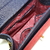 a imagem mostra o interior de uma bolsa feminina tiracolo e alça de mão em tecido jeans  com detalhes em vermelho