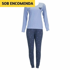 O pijama na imagem tem uma blusa de manga comprida azul clara com um coração escuro no peito superior esquerdo. As calças são de cor azul mais escura com vários corações claros estampados. Material suave para dormir.