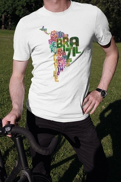 Homem usando uma camisa branca com design colorido que destaca a palavra "BRASIL" e países da América do Sul.