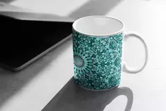 Caneca branca com estampa mandala em tons de azul e verde, posicionada sobre uma superfície clara.