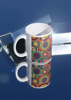 Caneca branca com estampas de mandala coloridas, refletindo sobre uma superfície espelhada.