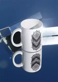 Caneca branca com design de mandala em preto, refletida em uma superfície espelhada