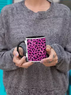 Caneca de porcelana com estampa animal print em tons de rosa, segurada por uma pessoa vestindo um suéter cinza.