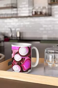 Caneca com design moderno em bolas abstratas nas cores rosa e branco, sobre uma bandeja de madeira.