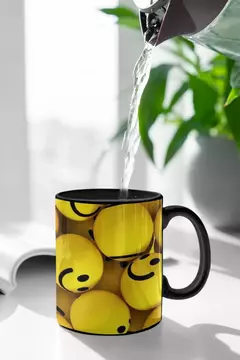 Caneca moderna com design de bolas amarelas sorridentes, sendo preenchida com água.