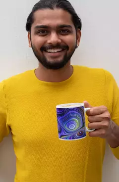 Homem segurando uma caneca com design abstrato de bolas coloridas, vestindo uma blusa amarela