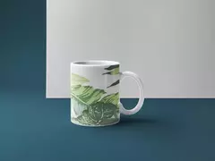 Caneca com design de folhagens em tons de verde, sobre fundo azul.