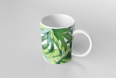 Caneca branca com estampa de folhagens verdes, ideal para bebidas quentes.