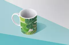 Caneca moderna com design de folhagens verdes, posicionada sobre uma superfície azul.