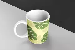 Caneca branca com estampa de folhas verdes em fundo amarelo