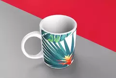 Caneca branca com design de folhagens verdes e flores exóticas, posicionada em um fundo cinza e vermelho.