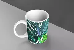 Caneca branca com estampa de folhagens verdes, posicionada em uma superfície cinza.